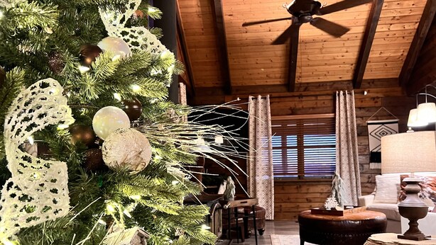 L’intérieur d’un chalet confortable, avec un sapin de Noël décoré, des meubles en bois et un ventilateur de plafond.
