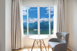 A room with a large window, a round table, and a grey chair.