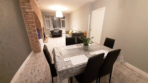 A dining area with a table set for four, surrounded by chairs, and a potted plant on the table. - Beautiful modern 3-Bed House in Birmingham (Birmingham)