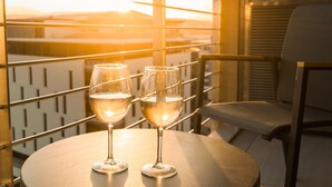 Two glasses of white wine on a round table with a metal railing and a chair in the background. - Black Marble - Menlyn Residence (Pretoria)