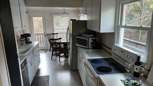 Une cuisine avec des meubles blancs, une cuisinière, un four à micro-ondes et un coin repas comprenant une table et des chaises.