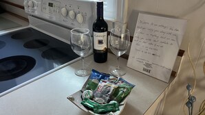Un comptoir de cuisine avec une bouteille de vin, deux verres, un mot et une assiette de collations.