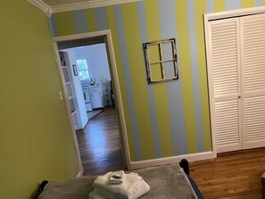 A room with a wooden floor, a white door, and a mirror on the wall.