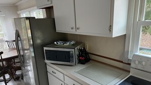 Une cuisine compacte équipée d’un réfrigérateur, d’un four à micro-ondes, d’une cuisinière et de placards.