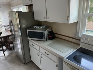 A compact kitchen with a refrigerator, microwave, stove, and cabinets.