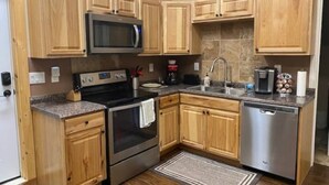 A kitchen with wooden cabinets, a stainless steel microwave, a stove, a dishwasher, and a granite countertop. - Heartland studio in North Pole, Alaska - plus extras  (North Pole)