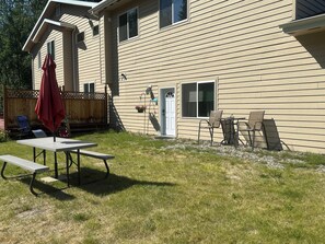 Ein Haus mit überdachter Terrasse, einem Tisch, Stühlen und einer kleinen Holzterrasse.