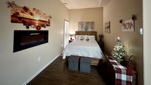 A bedroom with a bed, a TV mounted on the wall, a Christmas tree, and holiday decorations. - Heartland studio in North Pole, Alaska - plus extras  (North Pole)
