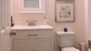 Un baño con un lavamanos blanco, un inodoro y cuadros en la pared.