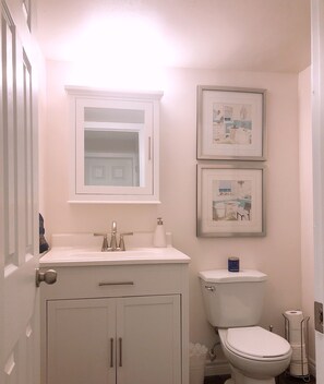 A bathroom with a white sink, a toilet, and framed pictures on the wall.