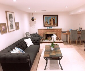 A living room with a black sofa, a coffee table, a fireplace, and a dining area with a table and chairs.