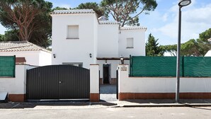 A white building with a black gate, a green fence, and a street lamp. - Chalet 'Poniente' with Pool and Garden (Roche)