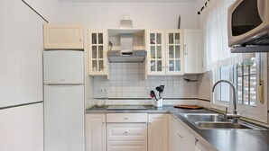 A kitchen with white cabinets, a stainless steel sink, and a built-in oven. - Chalet 'Poniente' with Pool and Garden (Roche)