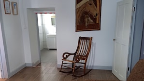 A living room with a brown sofa, a rocking chair, a marble coffee table, and a framed picture on the wall.