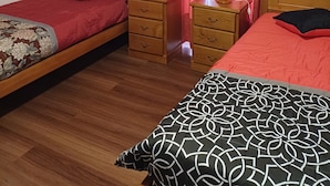 A bedroom with two single beds, wooden nightstands, and a red curtain.