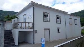 A two-story building with a balcony, a staircase, and a sign indicating private parking.