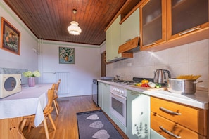 A kitchen with wooden cabinets, a stove, a microwave, and a dining area with a table and chairs.