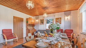 A dining area with a wooden table set for four, surrounded by wooden chairs.