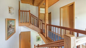 A wooden staircase with a railing, a door, and a framed picture on the wall.