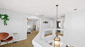 A modern interior with a high ceiling, a hanging plant, a red chair, and a hanging lantern. - Luxe 3 Bedroom Home with optional Heated Pool 🌊 6Mi to LV Strip!💫✨ (Las Vegas)