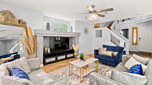 A modern living room with a fireplace, sofas, a coffee table, and a staircase. - Luxe 3 Bedroom Home with optional Heated Pool 🌊 6Mi to LV Strip!💫✨ (Las Vegas)