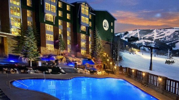 Un hôtel doté d'une piscine, d'un espace extérieur aménagé et offrant une vue sur une chaîne de montagnes enneigées.