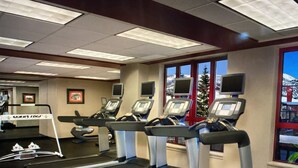 Une salle de sport équipée de tapis de course, de vélos d’exercice et d’un panneau indiquant un télésiège.