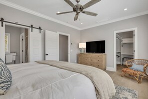 Een slaapkamer met een bed, een dressoir, een televisie, een stoel en een kast.