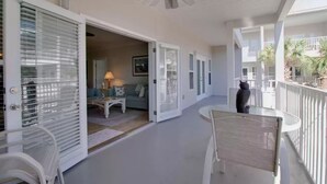Ein offener Balkon mit Deckenventilator, weißen Geländern und Blick ins Innere des Gebäudes.