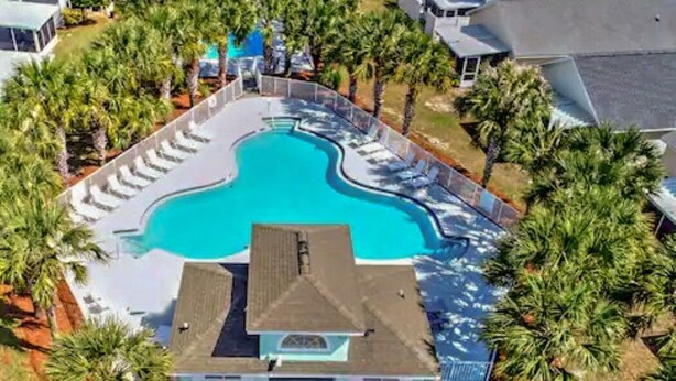 Oversigtsbillede af et resort med en central swimmingpool, omgivet af palmer og liggestole.