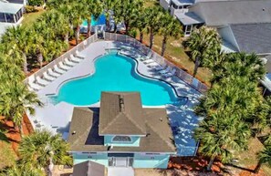 An aerial view of a resort with a central swimming pool, surrounded by palm trees and lounge chairs. - Our Beach House (Panama City Beach)