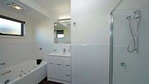Une salle de bain avec une baignoire, une douche, un lavabo et un miroir.