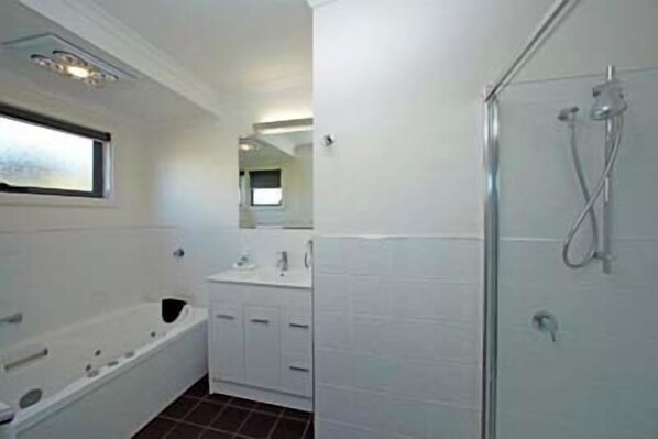 Une salle de bain avec une baignoire, une douche, un lavabo et un miroir.
