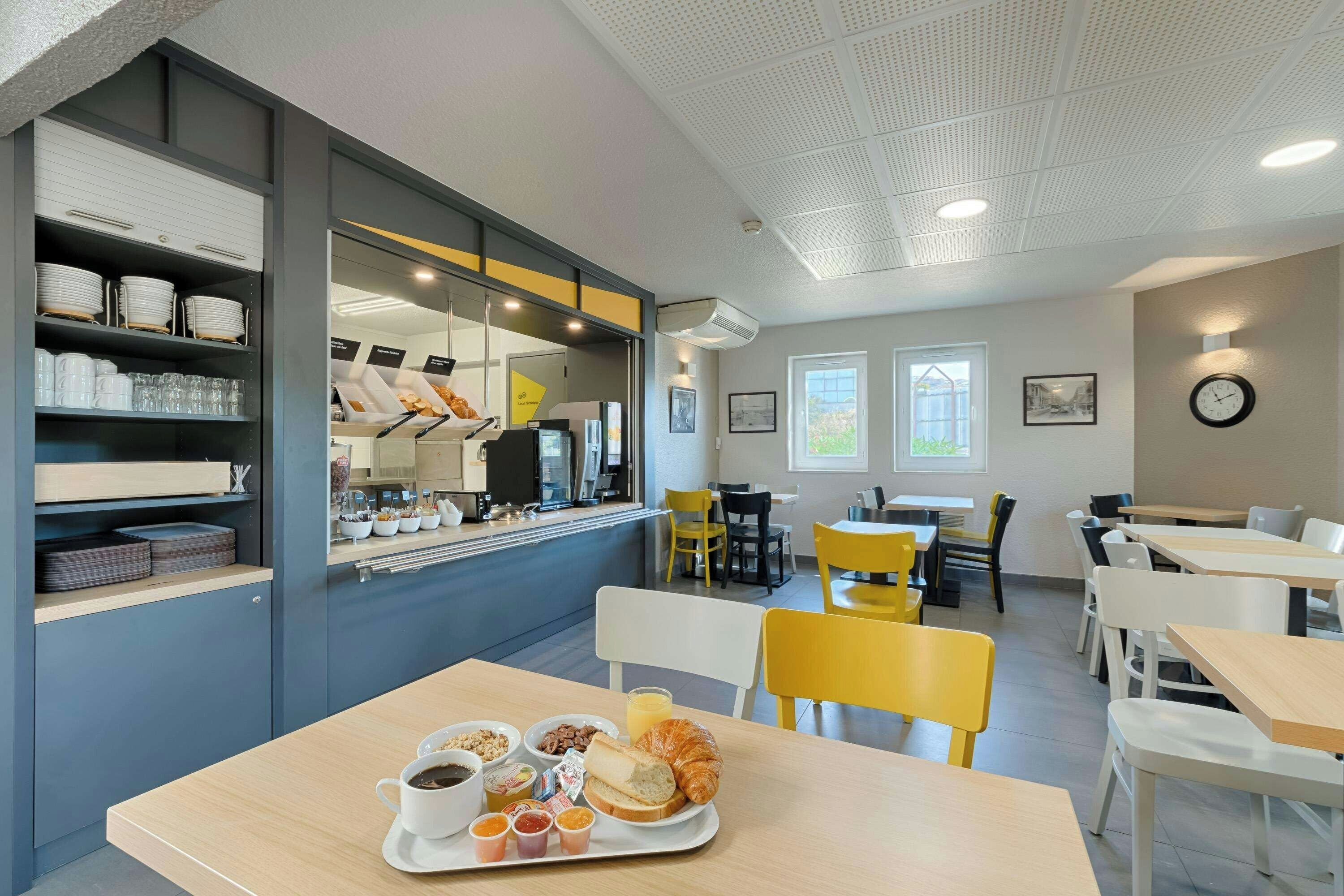 Ein modernes Café mit Frühstücksbuffet, Sitzgelegenheiten und Blick ins Freie.