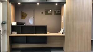 Ein Empfangstresen mit Computer, Kassiergerät und kleiner Theke. Schilder weisen auf Dienstleistungen und Preise hin.