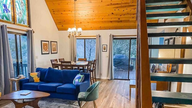 Amplia sala de estar con un sofá azul, piso de madera y una escalera que conduce a un nivel superior.