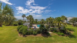 A residential area with a swimming pool, palm trees, and a view of the ocean.