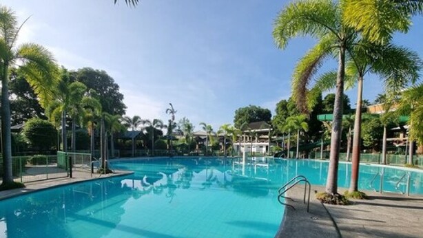 A clear blue swimming pool surrounded by palm trees and a covered seating area. - 4k Garden Resort by Cocotel (Santa Maria)