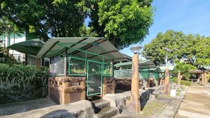 A zoo enclosure with a green roof and stone walls, surrounded by trees and a paved walkway. - 4k Garden Resort by Cocotel (Santa Maria)