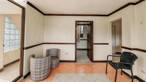 A hallway with a tiled floor, a door leading to another room, and two wicker chairs. - 4k Garden Resort by Cocotel (Santa Maria)