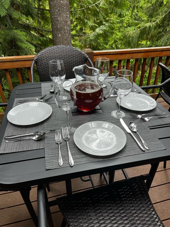 A table set outdoors with a pitcher, plates, cutlery, and glasses.