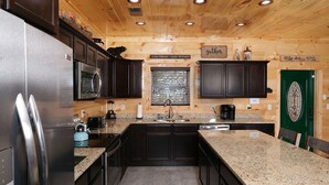 A modern kitchen with dark cabinets, granite countertops, stainless steel appliances, and a green door. - Private Poolside Bliss & Mountain Views! - A Splash of Heaven (Sevierville)