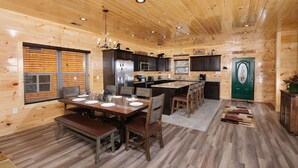 A wooden cabin interior with a dining area, kitchen, and a green door. - Private Poolside Bliss & Mountain Views! - A Splash of Heaven (Sevierville)