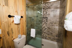 A bathroom with a glass shower enclosure, a toilet, and a bathtub.