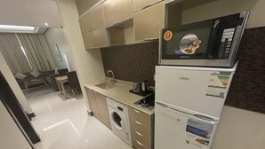 Moderni keittiö, jossa on sisäänrakennettu pesukone, mikroaaltouuni ja jääkaappi.