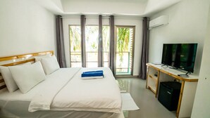 A hotel room with a bed, a desk with a television, and a window with curtains. - Lagoona Sunset (Maafushi)