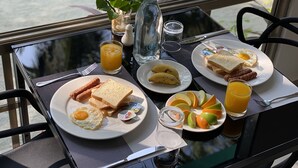 A breakfast table with plates of toast, eggs, sausages, bananas, and oranges. - Lagoona Sunset (Maafushi)