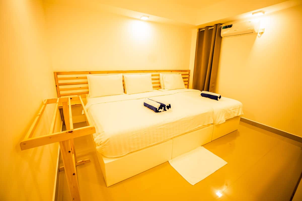 Ett hotellrum med en säng, en trästege, en vit handduk och en luftkonditioneringsanläggning.