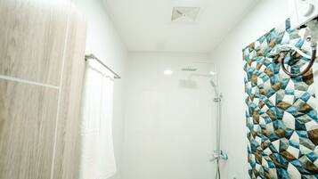 Un baño moderno con ducha, toallero y pared de azulejos estampados.