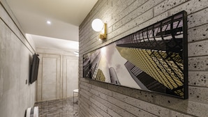 Ein Flur mit Backsteinwand, einem gerahmten Architekturprint, einer runden Wandleuchte und einem Handtrockner.